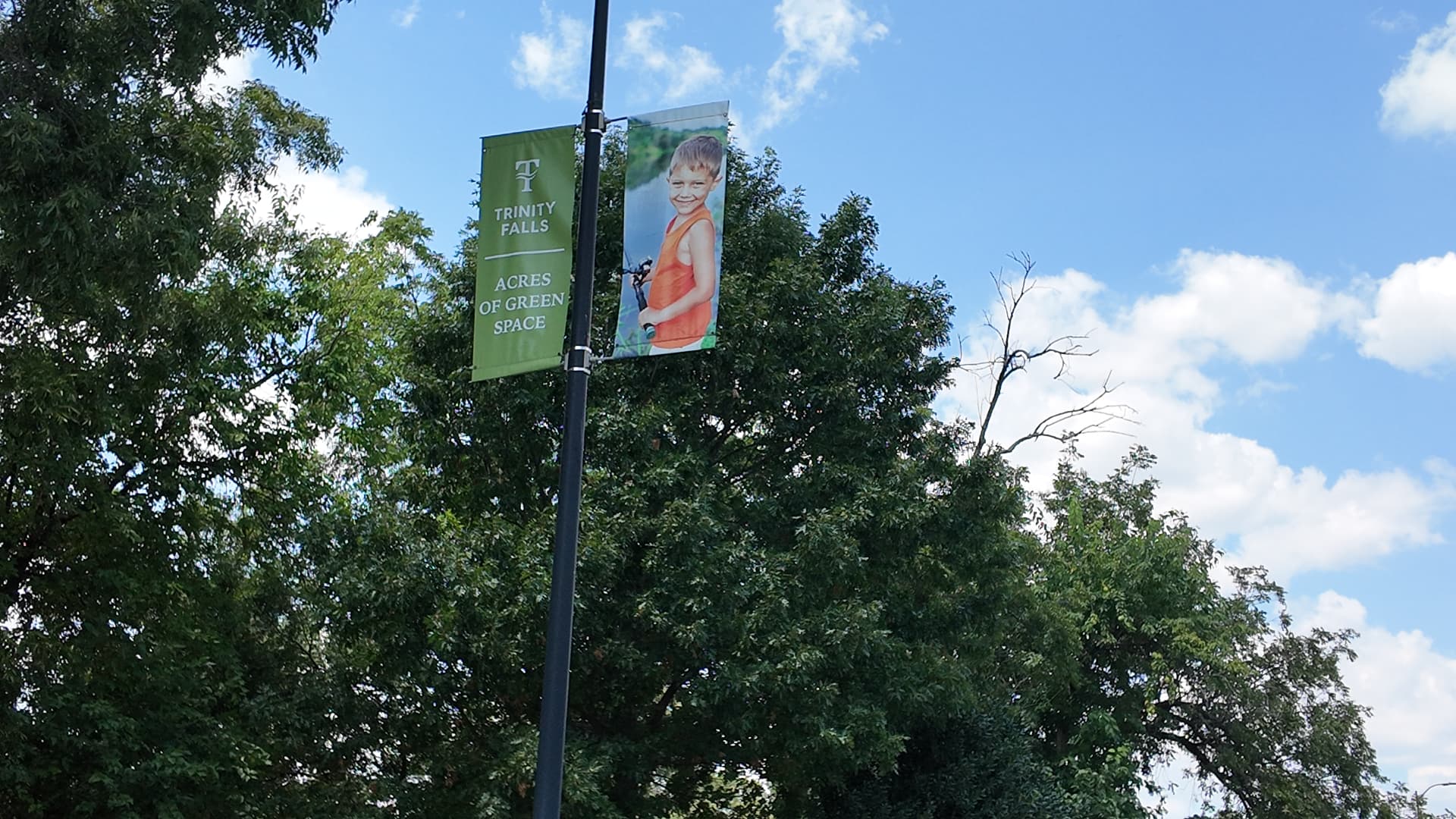 Trinity Falls 'Acres of Green Space' street banner among mature trees