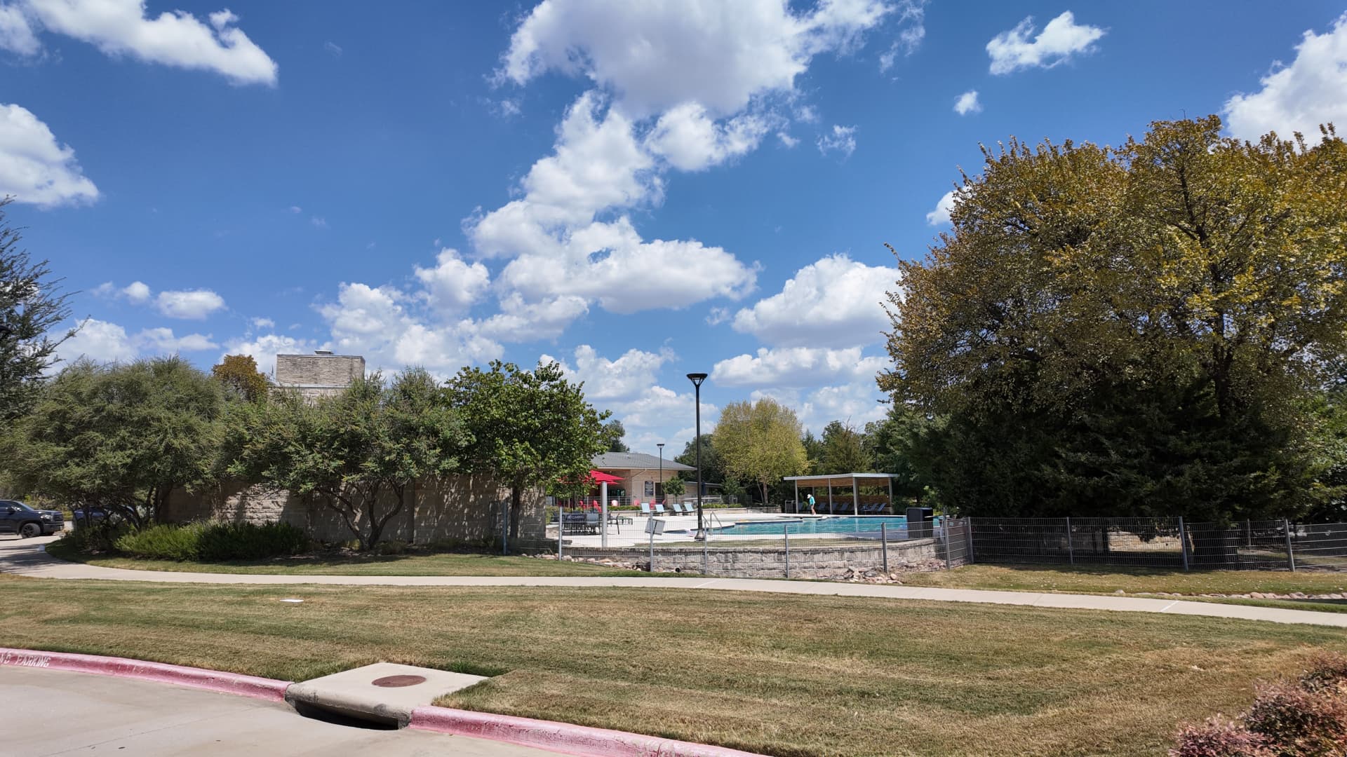 Open lawn and sidewalk beside the Trinity Falls community pool area