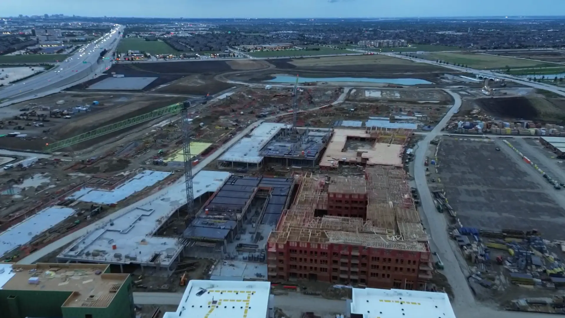 Aerial construction view of Fields West rising beside the highway in Frisco